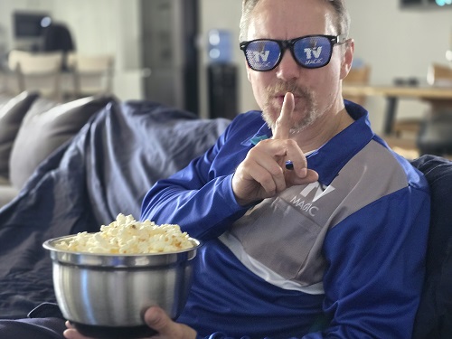 Technician going shhhhh, holding a bowl of popcorn. Wearing TV Magic sunglasses
