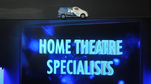 Large screen with "Home Theatre Specialists" on screen. Mini TV Magic van on top