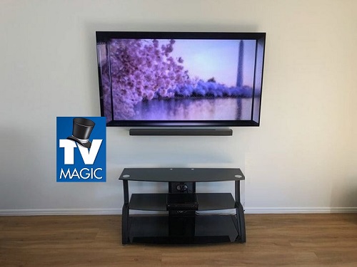 A wall mounted TV with floating soundbar beneath it. TV Magic logo below it