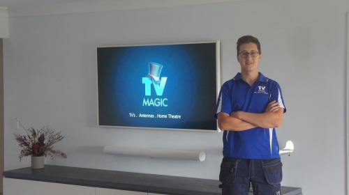 Technician standing in front of a new TV and soundbar installation he performed