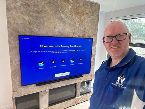 a photo of techncian - Craig, in front of a TV he just installed and setup