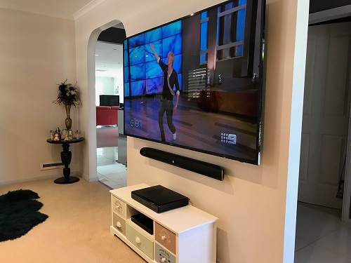 A side view of a TV mounted on a wall in a living room. Performed by TV Magic