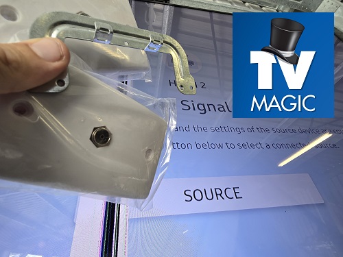 Technician holding up TV points in front of a TV with TV Magic logo in top right corner