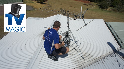 a technician on a tin roof installing an antenna. TV Magic logo in top left corner