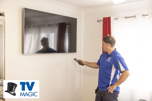 Technician holding remote in front of wall mounted TV