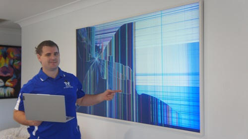 Technician pointing at a damaged TV, preparing to assess the damage.