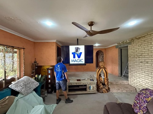 Technician with a ceiling mounted TV he installed