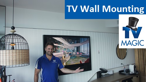 a technician in front of a wall mounted TV. Caption "TV Wall Mounting" in top right corner, along with TV Magic logo