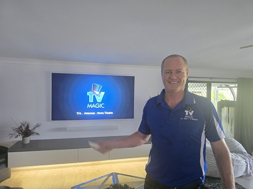 Technician in front of a TV, holding a TV remote