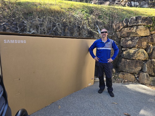 Technician with a massive TV ready for delivery.