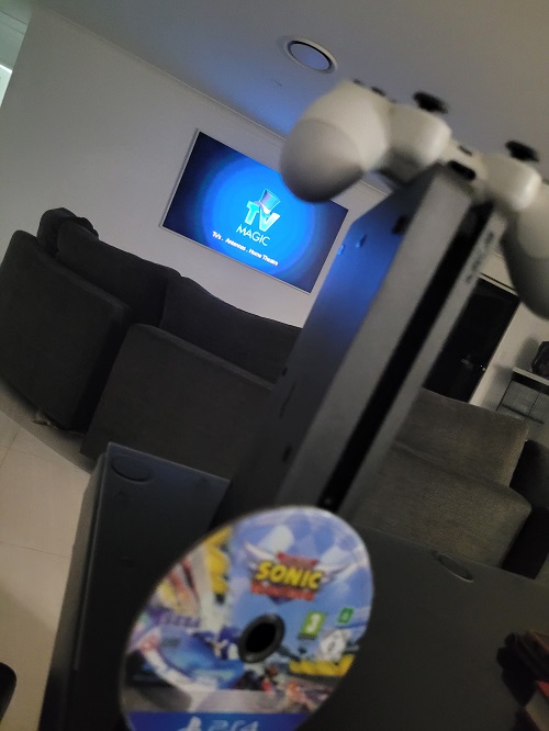 A gaming console with a TV in background with logo on screen.