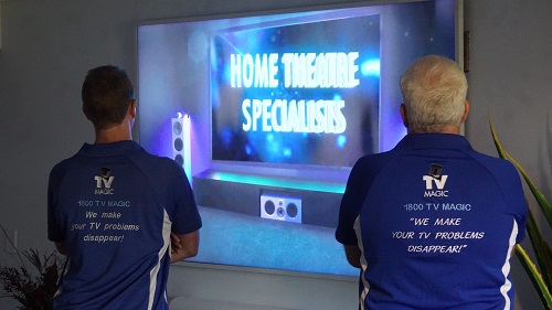 Technicians facing screen that says "Home Theatre Specialists"