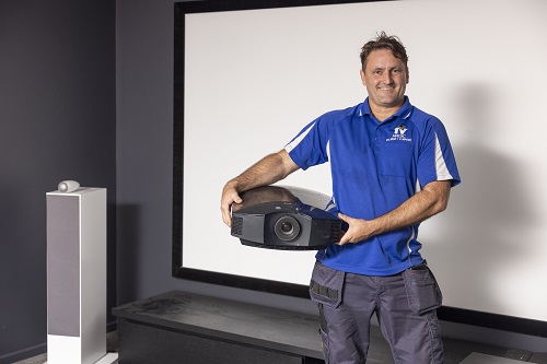 Technician holding a projector, ready for installation