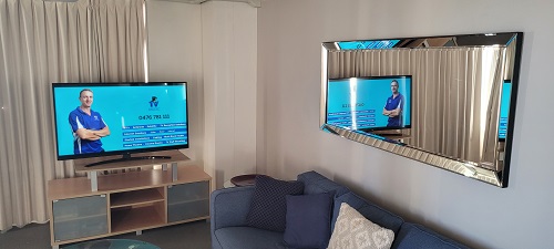 a TV on a display cabinet, with technician on screen with services displayed. Mirror on opposite wall. Living room setting