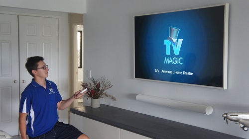 Technician holding a remote after installing and tuning a customers TV