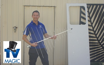 Jim holding an antenna in front of a garage