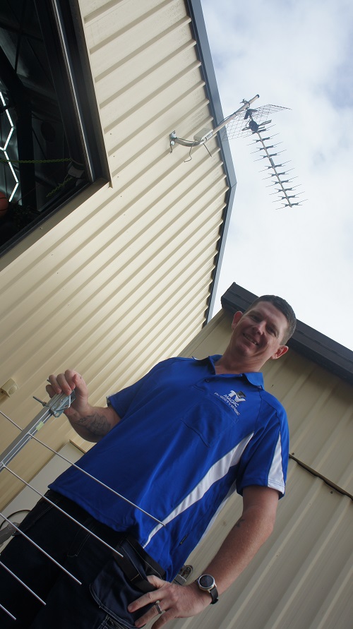 Technician standing below an antenna, holding an antenna