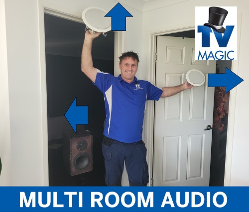 a technician with speakers in hand, arrows pointing to various different rooms. Caption "multi-room audio at bottom of photo. TV Magic logo in top right corner