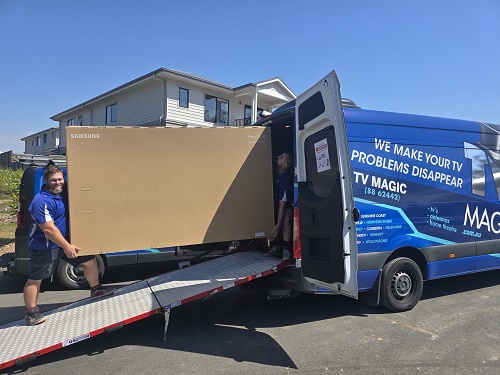 Technicians loading a large TV into the TV Magic van in Glendenning.