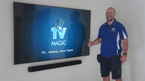 technician next to a wall mounted TV and sound bar