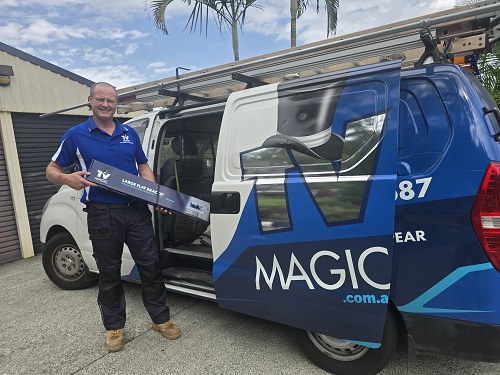 Technician holding a TV Magic mounting bracket next to his van