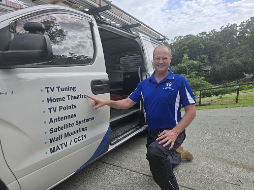 Technician Ben, pointing out his home theatre service on the door of his van.