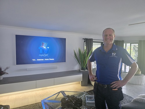 Technician Ben, standing in front of a TV he delivered and installed.