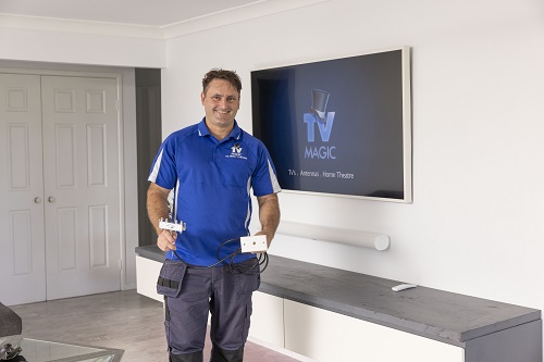 Technician in front of a TV entertainment area. He has a TV point ready for installation