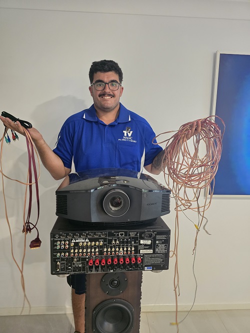 Technician standing with a projector and lots of cables.