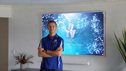 Technician in front of a smart TV he installed for a customer
