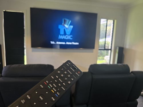 Wall mounted TV with remote held in front of it.